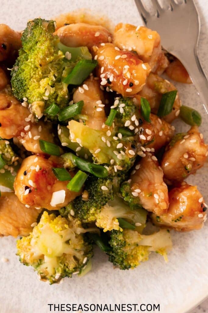 Close-up of honey garlic chicken and broccoli with sesame seeds, ready to eat.