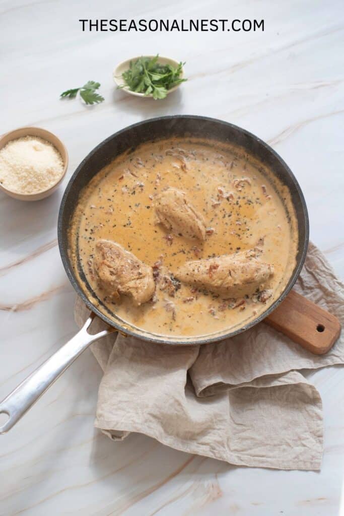 Creamy skillet with chicken breasts simmering in a rich sun-dried tomato sauce for Marry Me Chicken