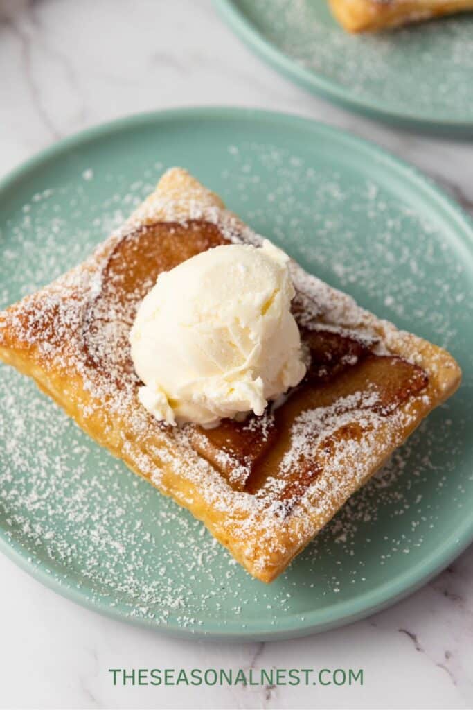 Flaky puff pastry apple tart topped with vanilla ice cream and powdered sugar.