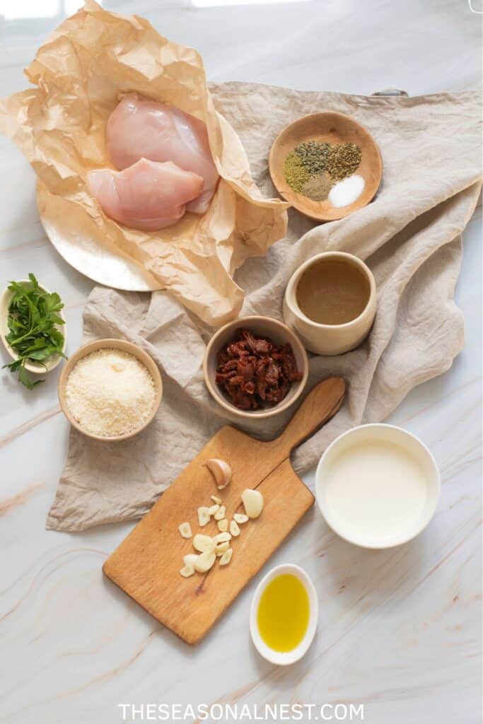 Merry Me Chicken ingredients including chicken breasts, sun-dried tomatoes, Parmesan, garlic, cream, and herbs.