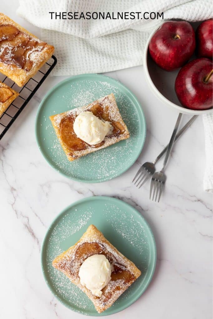 Homemade apple puff pastry tarts on plates with fresh apples on the side.