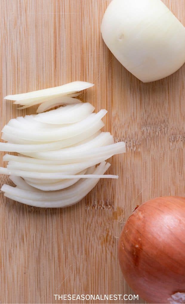 An onion cut in slices over a wooden background.