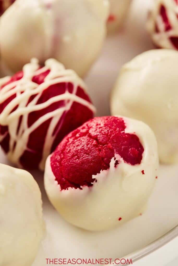 Overhead shot of red velvet truffles decorated with white chocolate drizzle.