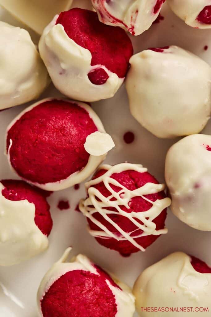 Close up of red velvet truffles coated in white chocolate with a creamy red center.