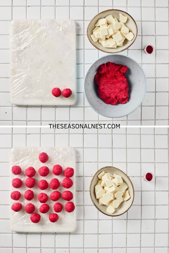 Red velvet truffle dough being rolled into balls on a tray with a bowl of white chocolate pieces.