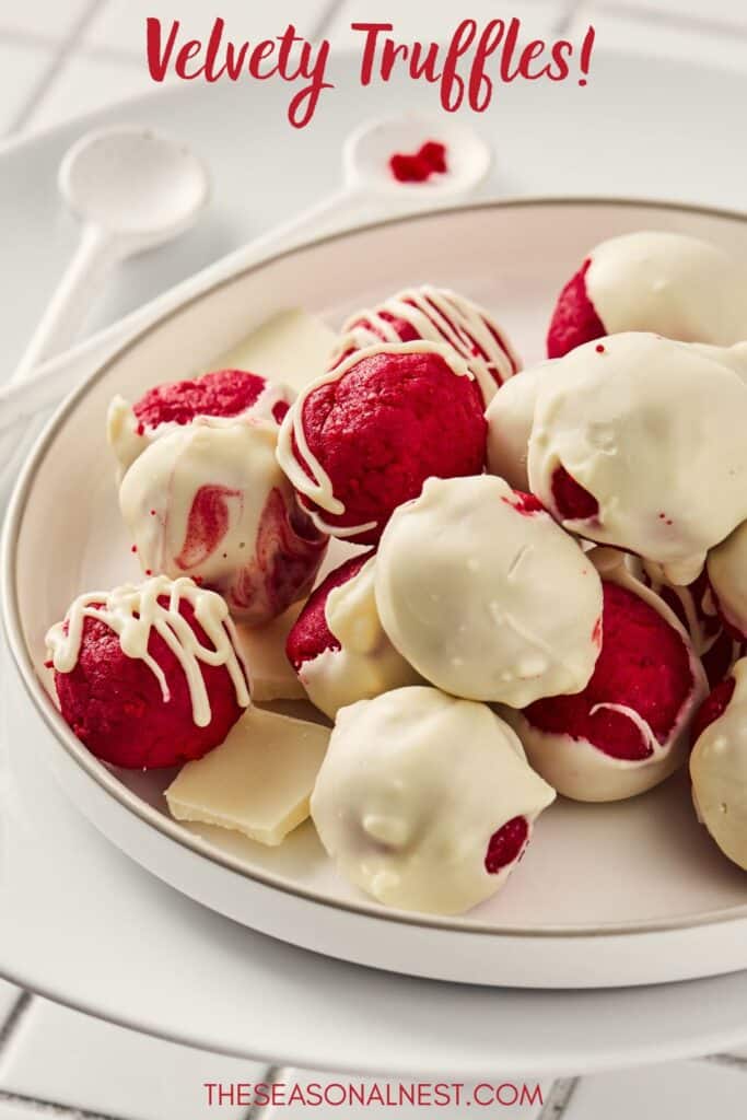 Plate of red velvet truffles coated in white chocolate with decorative drizzle.