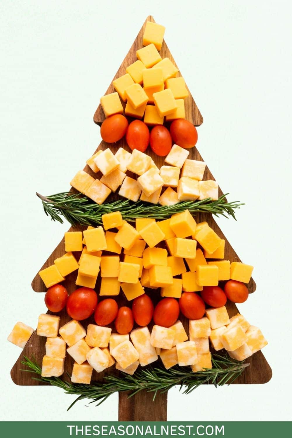 A Christmas Tree Cheese with rosemary springs over a Christmas tree board.