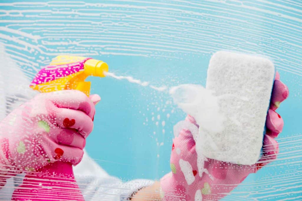 Cleaning spray with a cleaning sponge over a blue background