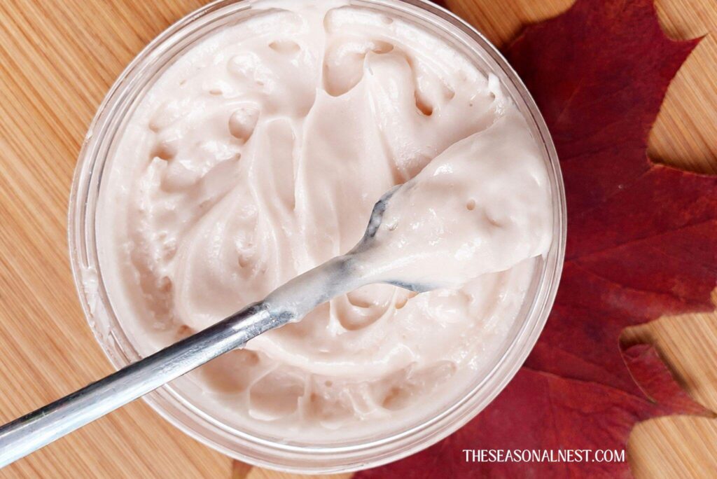 DIY maple cream in a container with a spoon with a maple leaf underneath.