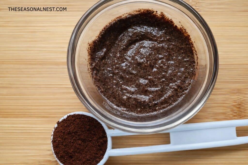 DIY coffee face scrub in a small bowl with a spoon full of coffee grounds.