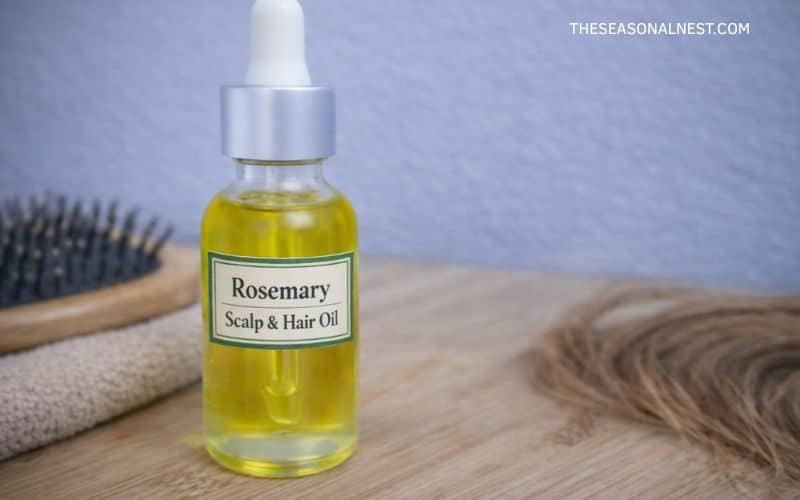 DIY hair oil recipe in a bottle with a brush and a piece of hair in the background.