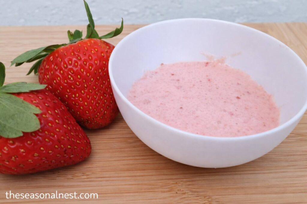 Homemade skin tightening remedy on a bowl and 2 strawberries.