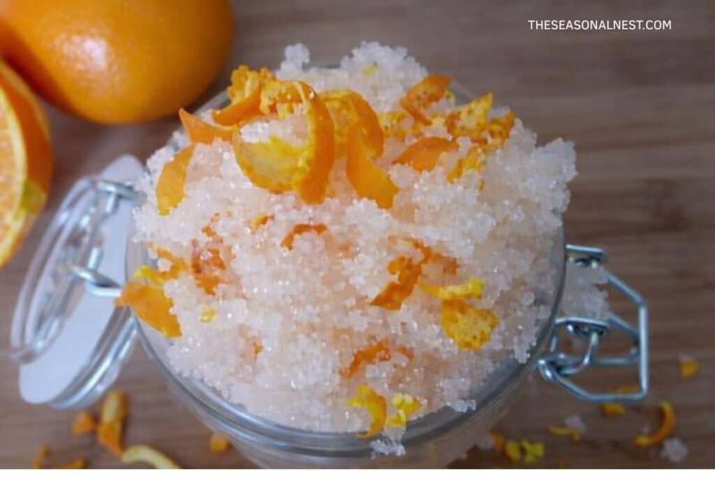 Homemade orange sugar scrub in an open glass jar.