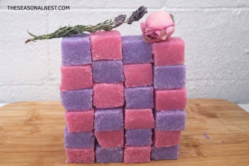 Homemade lavender and rose sugar scrub cubes with a rose and a lavender sprig on top.