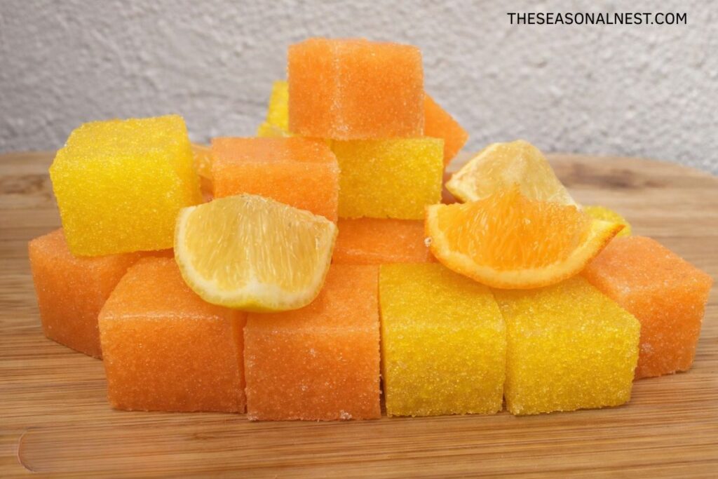 Homemade orange and lemon sugar scrub cubes with lemon and orange wedges.