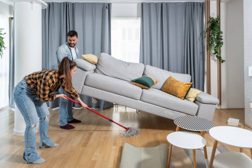 A couple mopping underneath the sofa.
