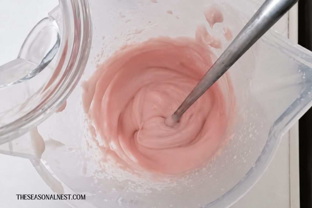 Adding rosewater to the melted wax.