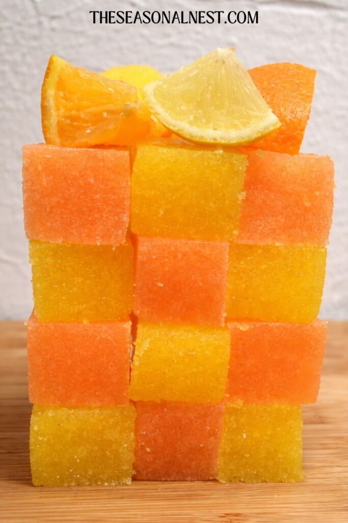 Lemon and orange sugar scrub cubes arranged in a tower with lemon and orange wedges on the top.