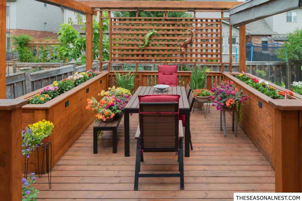 Small backyard deck with pergola, outdoor dining table and colorful planter boxes along the railing.