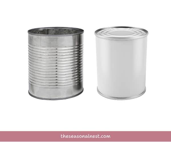 Two empty tin cans, one silver and one white, ready for a bucket décor Easter DIY project.