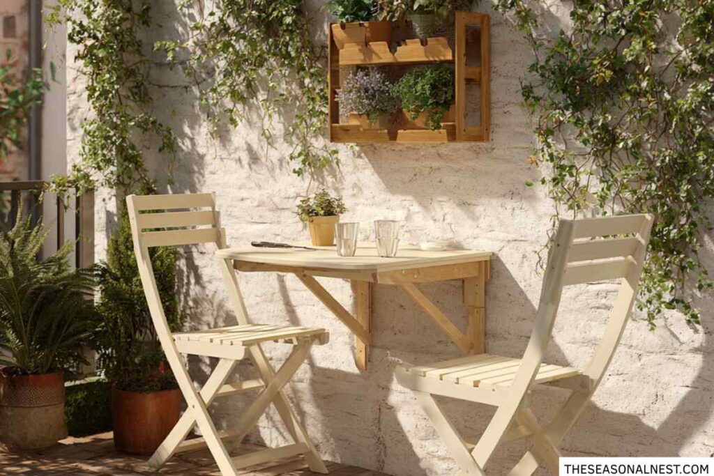Tiny patio with a wall-mounted folding table, two chairs, climbing plants, and small decorative planters.