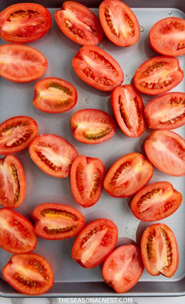 A handful of half fresh tomatoes on a baking tray.